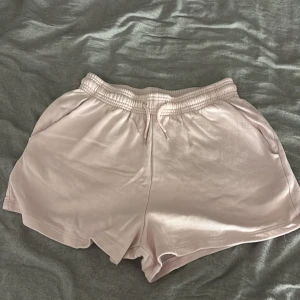 Ljusrosa fleece shorts från 157 - Mysiga ljusrosa shorts från 157 i storlek S. De har elastisk midja med snörning och är gjorda i mjuk fleece som är perfekt för chill dagar. Modellen är loose fit och har fickor på sidorna. Snygg enkel design som är lätt att matcha med hoodies eller t-shirts.