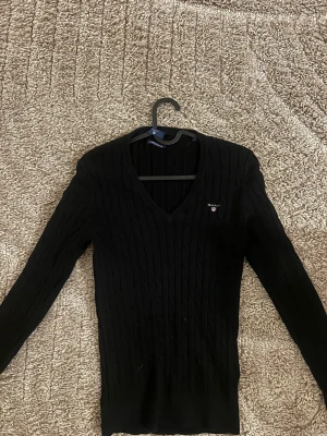 Gant tröja  -  svart tröja från Gant med V-ringning och diskret logga broderad på bröstet. Stilren & elegant tröja.