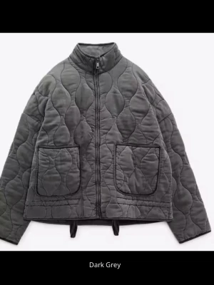 Mörkgrå vårjacka  - BYTE!! ja vill gärna byta storlek mot S, denna är L och passar om man villl ha den mer over size . Snygg mörkgrå pufferjacka med  mönster och två stora fickor framtill. Jackan har dragkedja, hög krage, jackan ser helt ny ut och använt ett få tal gånger. 