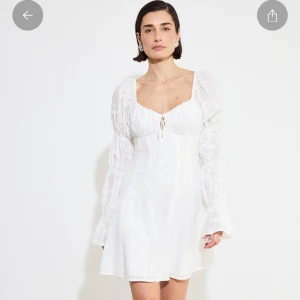 Vit kort klänning med spets och snörning - Superfin vit kort klänning. Klänningen har långa puffärmar, v-ringning och snörning framtill. Perfekt till studenten eller midsommar!💞Har prislapp kvar