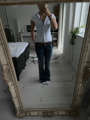 Vit-blå randig skjorta Brandy Melville - Kortärmad skjorta från Brandy Melville i vit och ljusblå randigt mönster. Skjortan har en figurnära passform, klassisk krage och knappar framtill. Tillverkad i mjuk bomull, perfekt för en fräsch och enkel stil. Originalpris - 280 kr