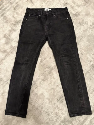 Svarta jeans från 157, rak modell - Säljer ett par svarta jeans från 157 med klassisk femficksdesign och raka ben. Jeansen har normal passform och är tillverkade i ett mjukt bomullsmaterial med lite stretch. Perfekta för dig som gillar en enkel och stilren look.