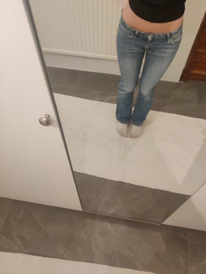 Blå bootcut jeans med låg midja - Säljer ett par ljusblå bootcut jeans med låg midja. Jeansen har klassisk femficksdesign och är tillverkade i ett mjukt denimtyg. Perfekta för dig som gillar en avslappnad och tidlös look. Dem är använda en del vilket syns. Har tyvärr vissa fläckar (finns på bild) men snygga i övrigt. Går nog även att sy ner. 