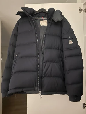  Moncler montgenevre mörkblå 6 (XL) - Unik mörkblå jacka från Moncler med klassisk pufferdesign och Moncler-logga på ärmen. Det är av modellen montgenevre och är i storlek 6 som ungefär motsvarar XL. Perfekt för kalla dagar. Jackan är givetvis äkta och jag kan skicka fler bilder. Priset är billigt på grund av små hål och repor men annars i bra skick, hör av er vid frågor eller funderingar så löser vi en scysst deal. 