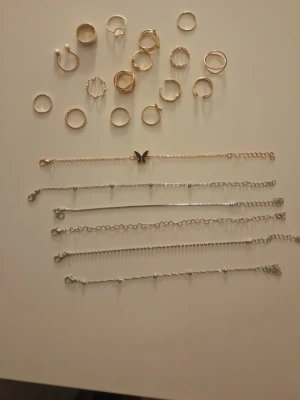 Mix av guldfärgade ringar - Säljer ett set med flera guldfärgade ringar i olika former och stilar. Några ringar har pärldetaljer, andra är släta eller har räfflade kanter. Perfekta för att mixa och matcha för en personlig look.