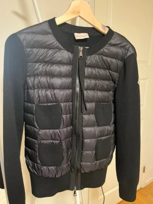 Svart Moncler cardigan  - Snygg svart jacka från Moncler med quiltad framsida och stickade ärmar. Allt medföljer, knappt använd 