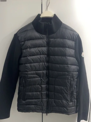 Moncler cardigan  - Säljer en svart quiltad cardigan från Moncler med stickade ärmar. Jackan har dragkedja framtill, två fickor med dragkedja och Moncler-logga på ärmen. Perfekt för dig som vill ha en stilren och exklusiv look.  Jag har etiketten också men är avklippt.                                 Priset kan diskuteras 😁