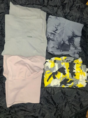 Paket, träningskläder, underdelar - Seamless tie Dye shorts, Design med rynkad rumpa, sparsamt använda. Camouflage TIGHTS, sparsamt använda. AIMN Ribbade högmidjade tights, har en oklar mindre fläck på benet (se bild) - använt skick. Laxrosa högmidjade tights,Design med rynkad rumpa, använda ett fåtal gånger 