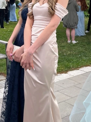 Champagnefärgad balklänning - Världens finaste figursydda balklänning i champange färg, den är ej tvättad efter jag använt den så på insidan längst ner vid fötterna är det märken men det är inget man ser. Väldigt bekväm och smickrande, skriv privat för mer bilder. Galge och påse till klänningen (som syns i bakgrunden) åker med. 🥰