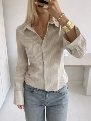 Beige och vit randig skjorta - Helt ny randig skjorta från Nakd i storlek XSS Figursydd modell med fin passform Slutsåld i butik, nypris 699kr💕