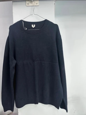 Mörkblå stickad tröja L - En enkel och stilren mörkblå stickad tröja i storlek L. Tröjan har rund halsringning och ribbade muddar vid ärmslut och nederkant. Perfekt för lager på lager under kyliga dagar. Sträck fram pga galjen.