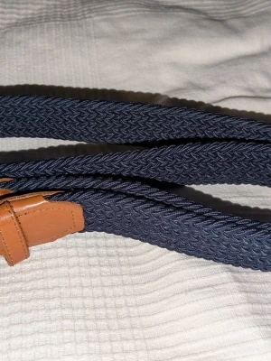 Bälte - Säljer ett snygg mörkblå flätat bälte med bruna ändor och metal sak för att hålla fast skärpet, den är 85 cm och en super fitt. Använd några fåtal gånger och bra skicka. Kan diskutera pris och bara ställa frågor 