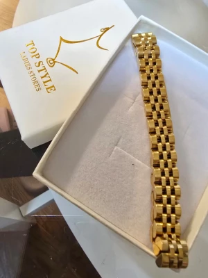 Oanvänt guldfärgat armband  - Snyggt guldfärgat armband från Top Style med klassisk länkdesign. Armbandet har en bred, rektangulär form.. Perfekt accessoar för dig som gillar stilrena och trendiga smycken. Armbandet är 21 cm lång 