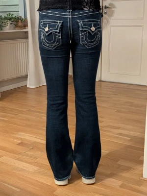 True religion jeans w24 - Säljer ett par mörkblå True Religion Becca jeans med bootcut och midwaist. Jeansen har tydliga vita kontrastsömmar. Storlek w24 dom är tyvärr förkorta för mig!💕