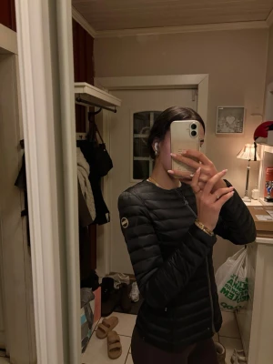 Svart pufferjacka från Colmar - Säljer en svart, stilren pufferjacka från Colmar. Jackan har quiltad design, rund halsringning och dragkedja framtill. Perfekt för dig som vill ha en lätt och snygg jacka till kyligare dagar. Diskret logga på ärmen och smidig passform.