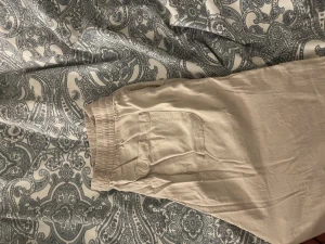 Beiga linnebyxor med snörning - Säljer ett par beiga linnebyxor från LST med elastisk midja och snörning framtill. Byxorna har en avslappnad passform och fickor på sidorna. Perfekta för chill dagar eller när du vill ha något luftigt och bekvämt.