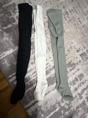 Tre ribbade knästrumpor i olika färger - Säljer tre par ribbade knästrumpor i svart, vitt och ljusgrått. Strumporna är mjuka och har en mysig, fluffig insida som håller dig varm. Perfekta att styla till kjol eller shorts för en trendig look. Passar för barn 3-7år