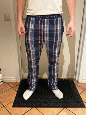 Rutig pyjamasbyxa från Gant L - Säljer ett par rutiga pyjamasbyxor från Gant i storlek L. Byxorna har marinblå, röda, vita och grå rutor samt resår i midjan med Gant-logga. Sköna och lätta, perfekta för chill dagar hemma.