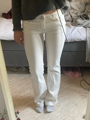 Vita bootcut jeans från Nelly  - Säljer ett lågmidjade Nelly jeans med bootcut passform och snygga kontrastsömmar på bakfickorna. Så snygga inför våren. Har fått lite smuts längst ner vid hälarna efter användning, men annars bra skick. 