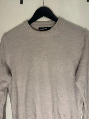 Beige stickad tröja från J.Lindeberg - Säljer en stilren beige stickad tröja från J.Lindeberg . Tröjan har rund halsringning, diskret logga på bröstet och ribbade muddar vid ärmslut och nederkant. Perfekt för lager på lager under höst och vinter. Tröjan var i storlek m från början men råka tvätta så skulle säga den passar mindre S eller XS 