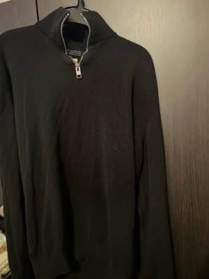 Svart half zip tröja Jack & Jones - Säljer en svart långärmad tröja från Jack & Jones med hög krage och half zip-dragkedja. Tröjan är i mjukt material och har en clean look som funkar till det mesta. Perfekt för dig som gillar stilrena basics.