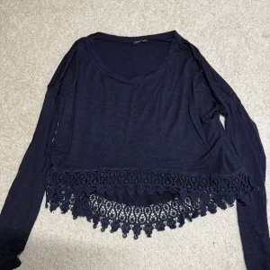 Mörkblå långärmad topp med spets - Säljer en mörkblå långärmad topp från Made in Italy. Toppen har en croppad passform och är dekorerad med bred spetskant nertill som ger en extra snygg detalj. Perfekt till jeans eller kjol för en chill men ändå stilsäker look.