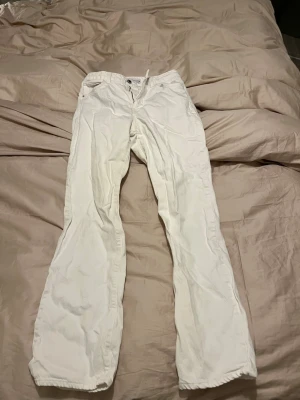 Vita raka jeans från Zara - Säljer ett par vita jeans från Zara i rak modell. Byxorna har klassisk femficksdesign, bälteshällor och stängs med dragkedja och knapp. Materialet är bomull och de har en clean look som är lätt att styla.
