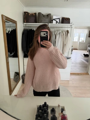 Ljusrosa stickad tröja - Supermysig ljusrosa stickad tröja med grov struktur och rund hals. Tröjan har en relaxed fit och långa ärmar, perfekt att slänga på sig när det är kyligt ute. Passar till både jeans och mjukisbyxor för en chill look.