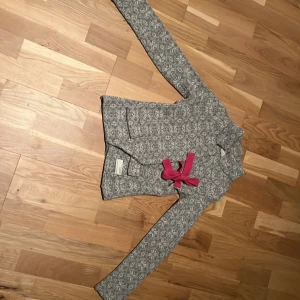 Jätte fin Grå mönstrad kofta med rosa rosetter från odd Molly - Säljer en jätte fin grå kofta från Odd Molly som jag tror inte säljs med denna design längre den är i vitt mönster och flera rosa rosetter som detaljer. Koftan har lång ärm, rund hals och broderad logga på bröstet. Materialet är stickat och känns mjukt och skönt. Jag har använt den flertal gånger när jag var yngre men den har hållit sitt skick fantastiskt jag säljer den då för att jag har växt ur den. Tröjan har inga skador alls på sig. 