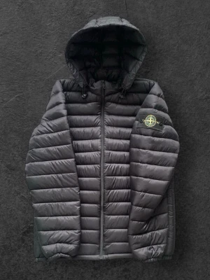 Svart pufferjacka från Stone Island - Säljer en svart pufferjacka från Stone Island med huva och dragkedja framtill. Jackan har det klassiska Stone Island-märket på ärmen och är en riktigt snygg jacka för att uppgradera din stil till nästa nivå. Jackan har ingen storleks lapp men jag uppskattar att det är en S. Därför har jag skänkt priset med 500kr. Läser du inte detta men köper jackan ändå och den inte passar så är det ditt fel.