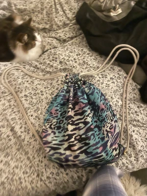 Leopardmönstrad ryggsäck med snörning - Cool gympåse/ryggsäck med leopardmönster i blå, lila och svart. Väskan har snörning som axelband och en praktisk dragkedja på sidan. Perfekt för att bära med sig det viktigaste till skolan eller träningen.