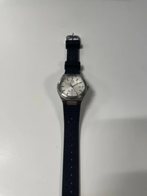 Timex klocka med svart silikonband - Snygg Timex armbandsklocka med rund silverfärgad boett i rostfritt stål och vit urtavla. Klockan har svarta timmarkeringar, datumvisning och ett svart silikonband med struktur. Perfekt för dig som gillar klassisk men sportig stil.