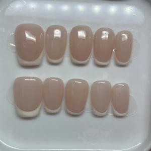 Beige lösnaglar i fransk stil - Säljer ett set med eleganta beige lösnaglar i fransk stil. De har en naturlig look med en mjuk övergång från beige till vit vid nagelspetsarna. Perfekta för en stilren och klassisk manikyr.