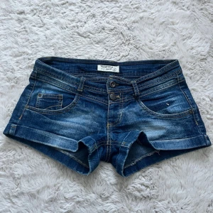 Vintage lowrise jeansshorts från Terranova - Snygga lowrise jeansshorts från Terranova med klassisk femficksdesign och uppvikta benslut. Shortsen har normal passform, låg midja och slitna detaljer för en avslappnad look. Perfekta för varma dagar och enkel att matcha med olika toppar. Grenhöjd 15cm, midjemått rakt över 37cm. Priset går att diskutera🤍🦢