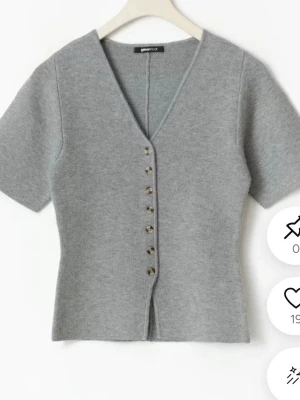 Grå kofta från Gina Tricot - Snygg grå kortärmad kofta från Gina Tricot med v-ringning och dekorativa knappar framtill. Koftan är figurnära och har en mjuk, stickad känsla som passar perfekt till jeans eller kjol. Enkel men trendig design som är lätt att matcha. Endast använd en gång och är som ny. Skriv om ni vill ha fler bilder!❤️