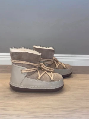 Beige boots från Inuikii - Snygga boots från Inuikii i färgen beige med rund tå, platt sula och grova snören. Fodrade med mjuk päls för extra värme, de har en stilren look med Inuikii-logga bak. Endast använda en gång. 