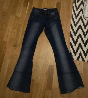 Mörkblå bootcut jeans med utsvängda ben - Snygga mörkblå jeans med breda utsvängda ben och klassisk femficksdesign. Jeansen har en markerad tvätt längs benen och är tillverkade i ett stretchigt denimtyg som ger en bekväm passform. Perfekta för dig som gillar retrostil och vill sticka ut. Dem är tall storlek s och är från gina tricot 