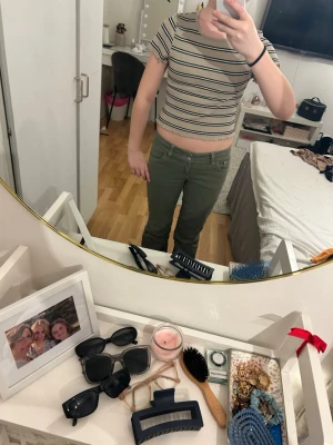 Beige randig croppad topp  - Superfin croppad topp i beige med svarta och vita ränder. Toppen är ribbad med korta ärmar och har söta volangdetaljer vid ärmslut och nederkant. Perfekt till jeans eller kjol för en chill look. Har storleken S men är kort och mer typ XS