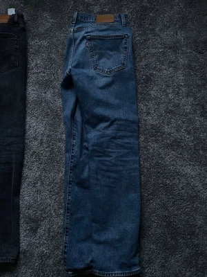 Levi's 502 blå jeans W32 L32 - Klassiska blå Levi's 502 jeans med rak passform och normal midja. Jeansen har fem fickor, Levi's ikoniska läderpatch bak och röd logotagg på bakfickan. Perfekta för en avslappnad och tidlös stil. Dom har spruckit i mitten av jeansen men enkelt att laga ihop, titta på en YouTube video så går det på 5 minuter, pga använder inte dom längre! 