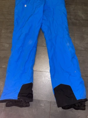 Blå täckbyxor från 8848 Altitude - Snygga blå täckbyxor från 8848 Altitude med svarta förstärkningar vid bensluten och dragkedja vid fickan. Perfekta för vinterns alla äventyr och håller dig varm och torr i backen.