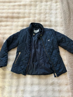 Marinblå quiltad jacka från Gant - Fin höst/vårjacka för barn i storlek 116. Den är i bra skick. 