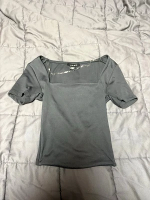 Svart topp med fyrkantig ringning från Amisu - En svart, enkel topp från Amisu i storlek XXS. Toppen har en snygg fyrkantig ringning och korta ärmar. Materialet känns mjukt och stretchigt