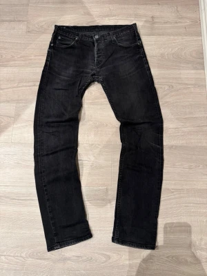  Lee jeans - Säljer ett par svarta Lee Powell jeans i storlek W33 L34. Klassisk femficksmodell med raka ben och snyggt Lee-läderpatch bak i midjan. Jeansen har en mörk tvätt och är tillverkade i slitstarkt denimtyg. Perfekta för dig som gillar en enkel och clean look.