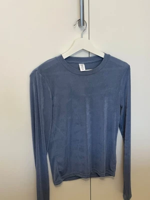 Blå långärmad topp från C.W. - Säljer en mjuk och stretchig blå långärmad topp från C.W. Toppen har rund halsringning och är gjord i ett sammetsliknande material som ger en snygg lyster. Perfekt att styla med jeans eller kjol för en chill look.