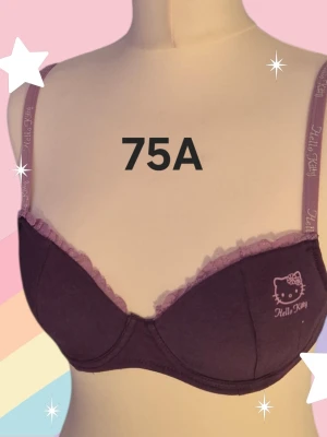 Lila Hello Kitty bh 75A - Söt lila Hello Kitty bh från Sanrio med spetskant upptill och tryckt Hello Kitty-logga på ena kupan. Axelbanden är dekorerade med Hello Kitty-tryck och bh:n är gjord i mjuk bomullsmix för extra komfort. Tunna kupor. Varan är oanvänd och kommer från ett konkurslager från 2000-talet. I många fall är prislappen kvar (se bild). Har fler annonser och bra bundlerabatt vid köp av flera.