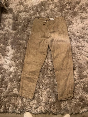 Beige linnebyxor från S.C.W, storlek S - Säljer ett par beige linnebyxor från S.C.W i storlek S. Byxorna har dragsko i midjan, raka ben och fickor både fram och bak. Perfekta för en chill och avslappnad stil. Materialet är svalt linne och färgen är naturligt beige. Mycket bra skick. Använd en gång i somras.