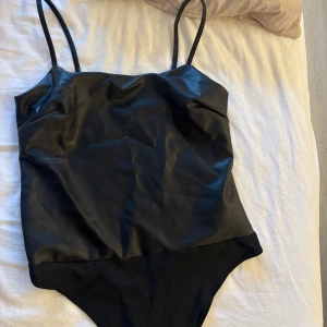 Svart body i skinn/läder  - En svart läder/skinn body, sitter jätte fint vid brösten och jätte bekväm men aldrig använt så utan bara testat inför en fest men sen aldrig använde