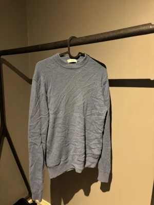 Ljusblå stickad tröja från MNG - Säljer en ljusblå stickad tröja från MNG i italienskt garn. Tröjan har rund halsringning, ribbade muddar och sitter slim på kroppen. Perfekt till jeans för en clean och enkel look.