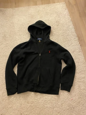 Ralph Lauren zip hoodie  - En svart Ralph Lauren zip hoodie i barnstorlek\XS, perfekt för alla olika stilar 