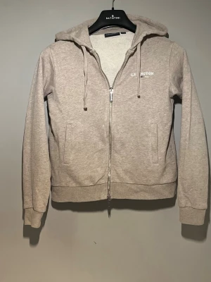 Lexington zip hoodie - Hej! Säljer en stilren beige zip hoodie från Lexington. Tröjan har tvåvägsblixtlås som ger en unik touch. Tillverkad i 100 % bomull och i mycket gott skick utan några skador då den knappt använts. Köpt för 899 kr. Fler bilder finns – bara att höra av sig vid minsta fundering!!